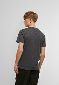 Kohlegraues Baumwoll-T-Shirt mit kurzen Ärmeln und Rundhalsausschnitt. Es hat eine klassische Passform und eine glatte Struktur. Keine sichtbaren Muster oder Akzente.