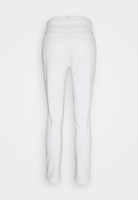 Jean slim blanc vu de dos, avec deux poches arrière et passants de ceinture, sur un fond clair.