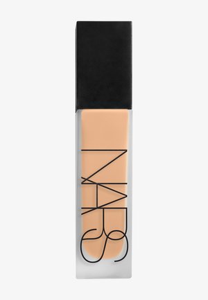 Flacon en verre rectangulaire de fond de teint liquide beige avec logo NARS noir et bouchon noir mat, posé debout sur fond blanc.