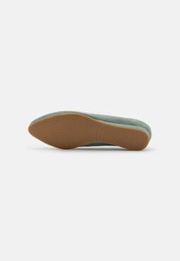 Scarpa piatta in suede verde con punta arrotondata e suola in gomma testurizzata. La suola presenta un grip a motivo per garantire stabilità.