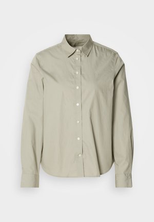 Light beige button-up shirt made of cotton. Features a classic collar, long sleeves, and a curved hem. Subtle branding on the chest.
