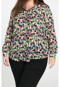 Blouse à manches longues colorée présentant un motif abstrait multicolore sur un fond clair. Confectionnée en tissu léger avec une coupe décontractée.