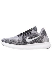 Scarpe sportive a maglia bianco e nero con suola bianca, lacci neri e logo swoosh argentato di lato. Parte superiore testurizzata per traspirabilità.