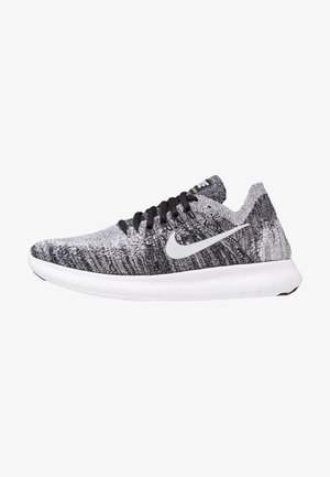 Scarpe sportive a maglia bianco e nero con suola bianca, lacci neri e logo swoosh argentato di lato. Parte superiore testurizzata per traspirabilità.