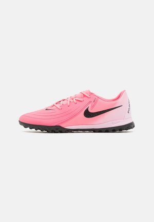 Zapatilla de fútbol Nike de color rosa brillante con logo swoosh negro, suela de goma negra y texto "Phantom" en el talón, mostrada de perfil.