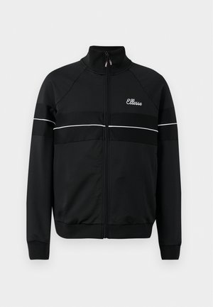 Chaqueta de entrenamiento negra con alto cuello, cremallera frontal y rayas blancas en el pecho. Presenta un logo en el lado izquierdo.