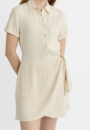 Vestido de camisa de lino beige con cuello, mangas cortas, botones en la parte delantera, un bolsillo en el pecho y un cinturón atado en la cintura. Textura suave.