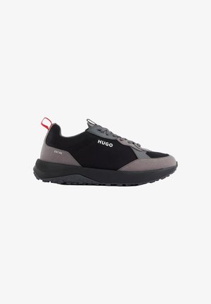 Heren zwarte en grijze Hugo sneaker met rode hieltab, veterontwerp en dikke gestructureerde zool. Branding omvat "HUGO" en "EST. 93" details.