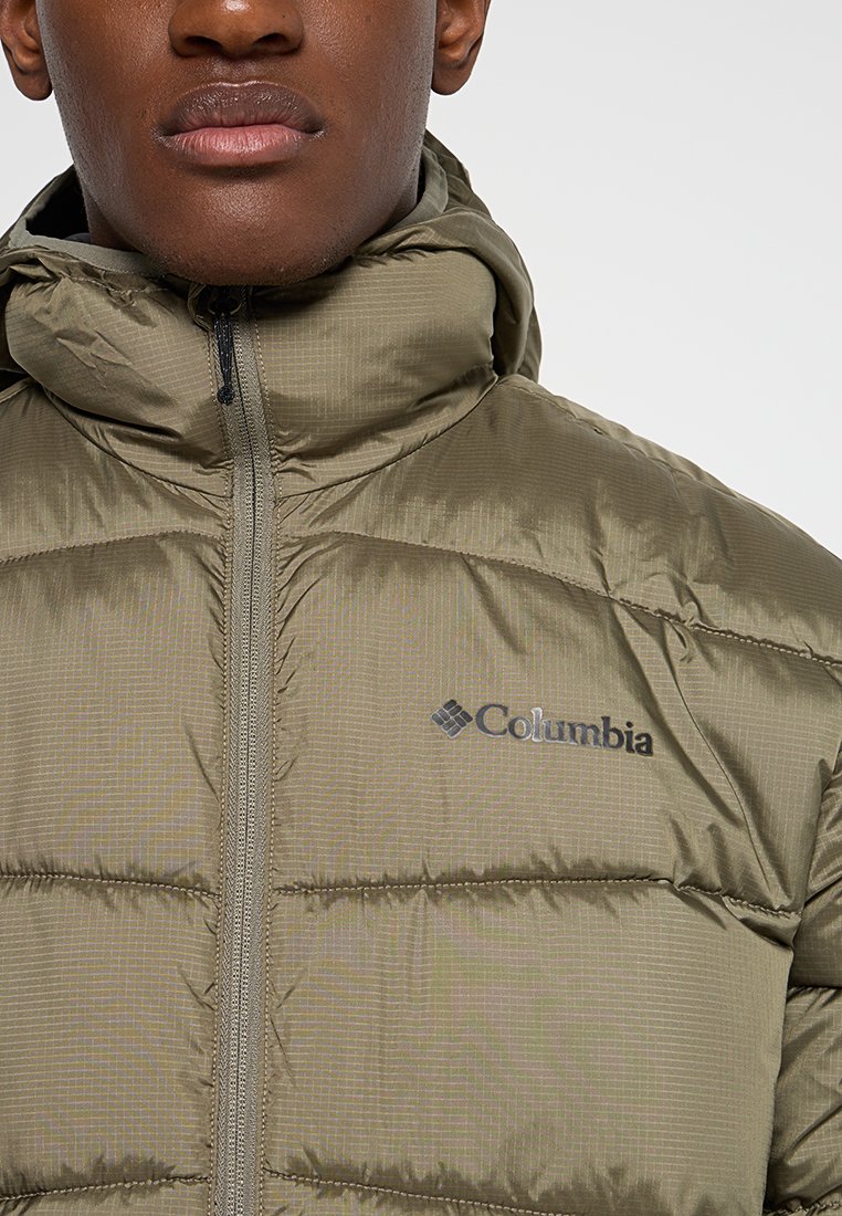 Chaqueta de plumas en verde olivo, con secciones acolchadas horizontales, una cremallera completa y el logo de Columbia en negro en el lado izquierdo del pecho.