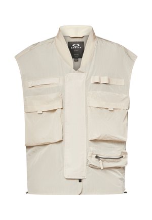 Beige Oakley-vest med flere frontlommer, en lynlåslomme og en høj krave, designet til funktionelt udendørsbrug.