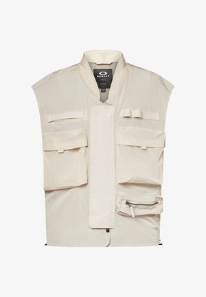 Beige Oakley-vest met meerdere voorzakken, een ritssluiting en een hoge kraag, ontworpen voor functionele buitenkleding.