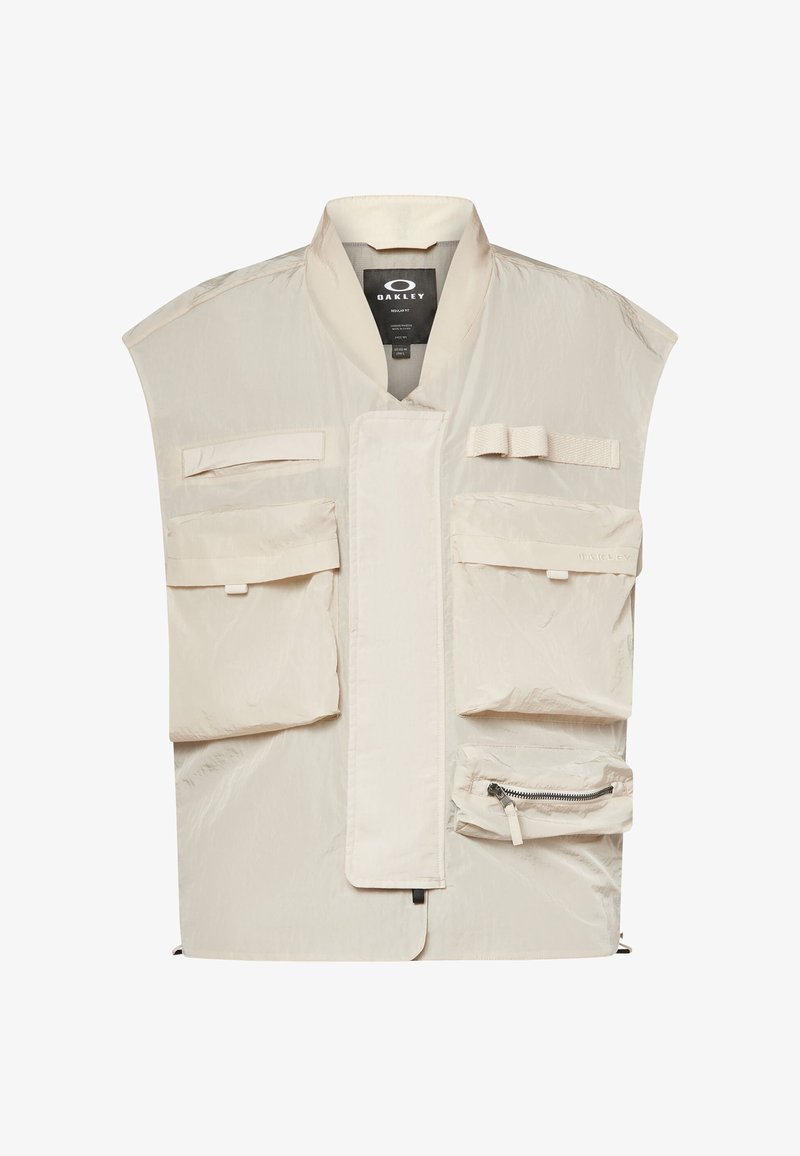 Beige Oakley-vest med flere frontlommer, en lynlåslomme og en høj krave, designet til funktionelt udendørsbrug.