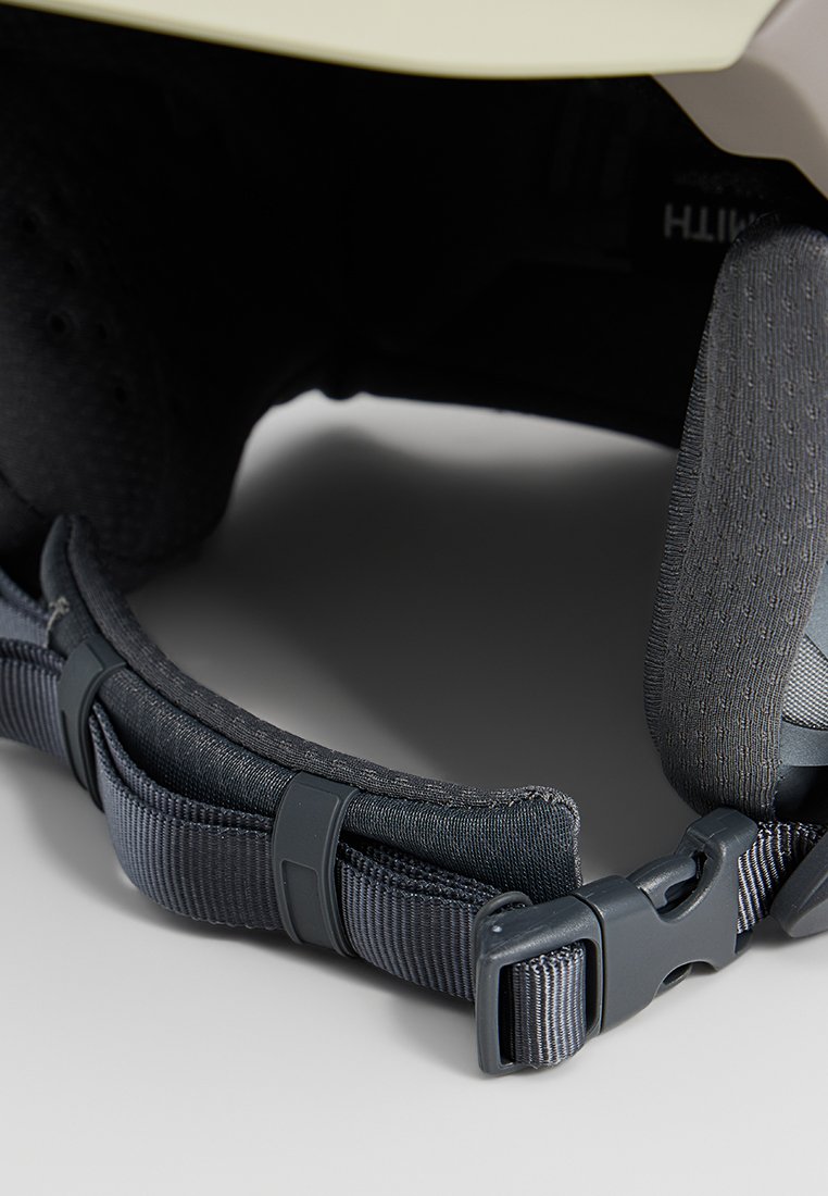 Regulowany czarny pasek z teksturowanym szarym wyściółką, z plastikową klamrą i miękką podszewką, pokazana spód hełmu ochronnego.