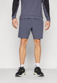 Grå atletiske shorts med sidesøm, parret med en matchende grå top og sorte sneakers. Stoffet ser let og glat ud.