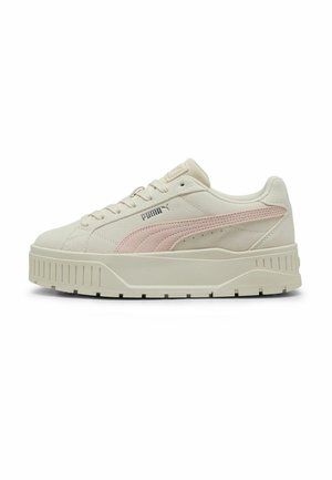Baskets Puma en crème et rose doux, avec une tige en cuir lisse, un embout arrondi, et une semelle épaisse et texturée avec des rainures horizontales.