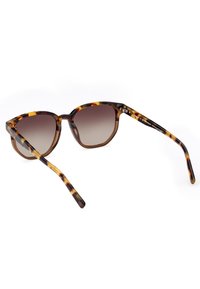 Gafas de sol marrón carey con un marco hexagonal, lentes degradados y varillas delgadas que presentan patrones moteados en tonos oscuros y claros.