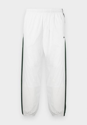 Biele športové nohavice s tmavozelenými bočnými panelmi. Ľahký materiál, elastický pás a sťahované lemy. Obsahujú sieťovinovú textúru na bočných paneloch.