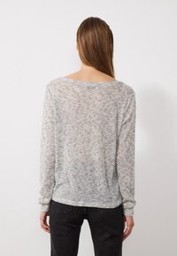 Leichtes, graues Stricktop mit lockerer Passform, langen Ärmeln und Rundhalsausschnitt, das ein dezentes Texturmuster und weichen Stoff aufweist.