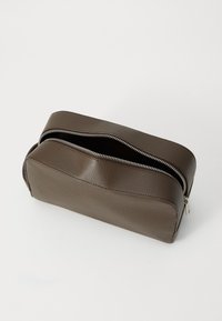 Pochette rectangulaire en cuir marron avec une finition texturée, deux zips et des bords arrondis. Le haut ouvert révèle le compartiment intérieur.