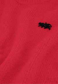 Roter strukturierten Pullover mit einem Rippmuster, versehen mit einem schwarzen Tieremblem auf der linken Seite. Weiches Material, Rundhalsausschnitt-Design.