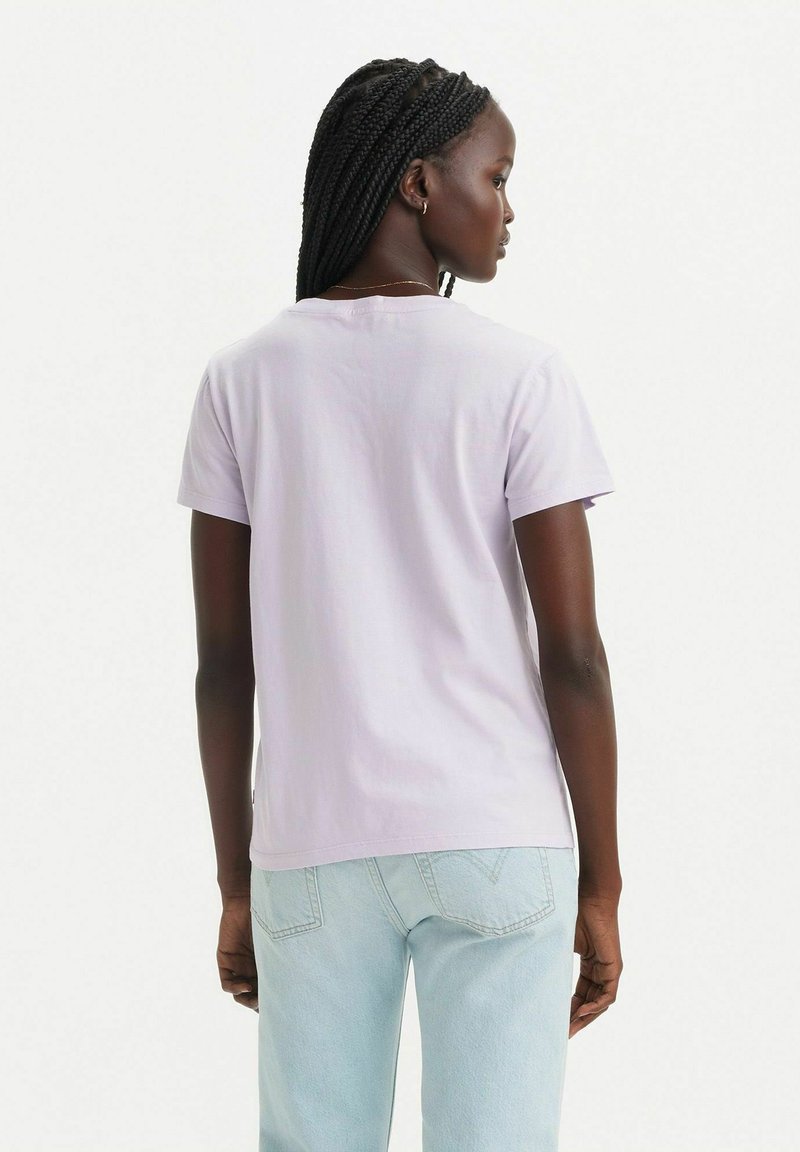 T-shirt corto viola chiaro con collo rotondo, realizzato in cotone. Texture liscia e vestibilità rilassata, abbinato a jeans blu chiaro.