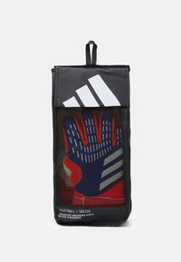 Borsa in rete nera con una parte frontale trasparente, contenente guanti da portiere rossi e blu. Strisce e testo bianchi Adidas visibili sulla borsa.