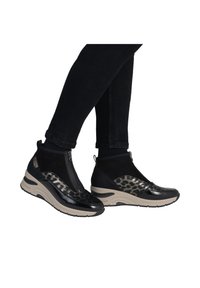 Bottes chelsea noires et à imprimé léopard avec une finition en vernis lisse, des côtés élastiques et une semelle chunky beige. Détail de fermeture éclair sur le côté.