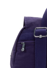 Lila tygryggsäckshörn med dragkedjefack och justerbar rem som har en metallspänne och en dragkedjehandtag med stjärnmönster.