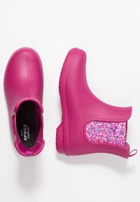 Stivaletti impermeabili rosa con una texture liscia, dotati di un pannello laterale con motivo glitterato e una suola in gomma testurizzata per una migliore aderenza.