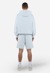 Lys blå hettegenser og matchende shorts laget av mykt stoff. Hette-design, løs passform, ribbestrikkede mansjetter og kantdetaljer.