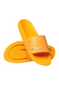 Paire de sandales slides Havaianas d'un orange vif avec semelles texturées et logo blanc sur les larges bandes, isolées sur fond blanc.