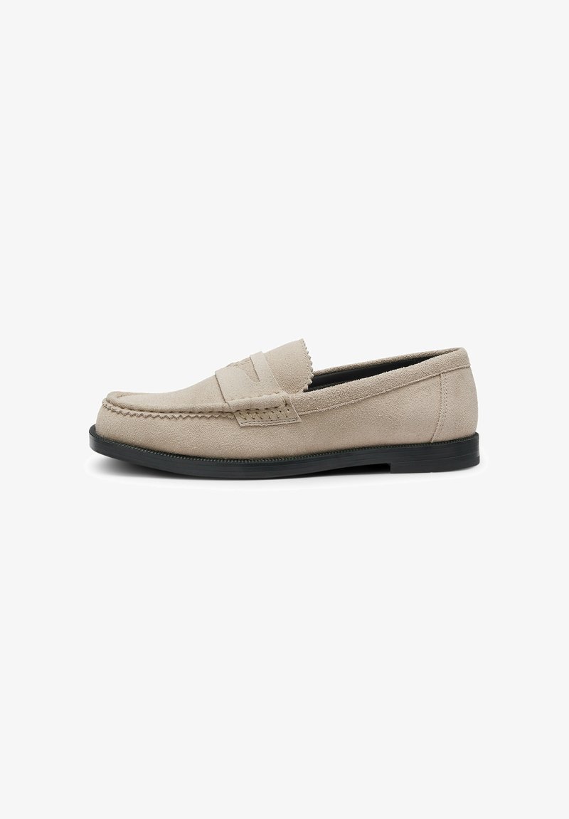 Mocassin pour homme en daim beige avec semelle noire, couture mocassin et détail de sangle sur le dessus, présenté de profil.