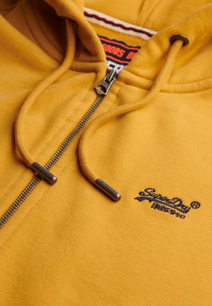 Sudadera amarilla de Superdry con cremallera frontal, cordones y logo bordado en el pecho.