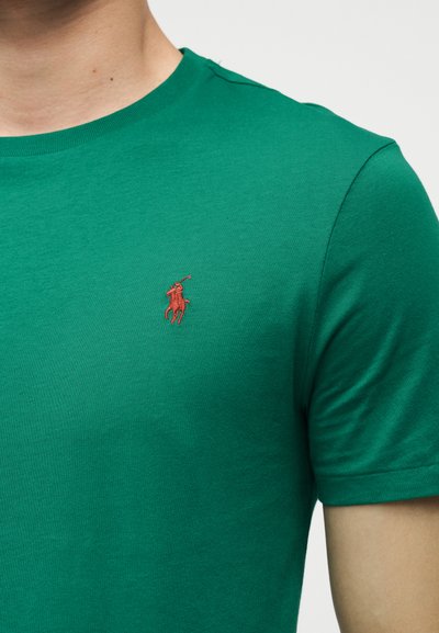 Πράσινο t-shirt με στρογγυλή λαιμόκοψη και κοντά μανίκια, με μικρό κόκκινο κεντητό λογότυπο παίκτη πόλο στο αριστερό στήθος.