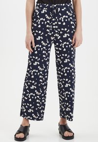 Marinblå vida byxor med liten blommönster i vitt och beige. Har ett elastiskt midjeband med dragsko. Lättviktsmaterial.