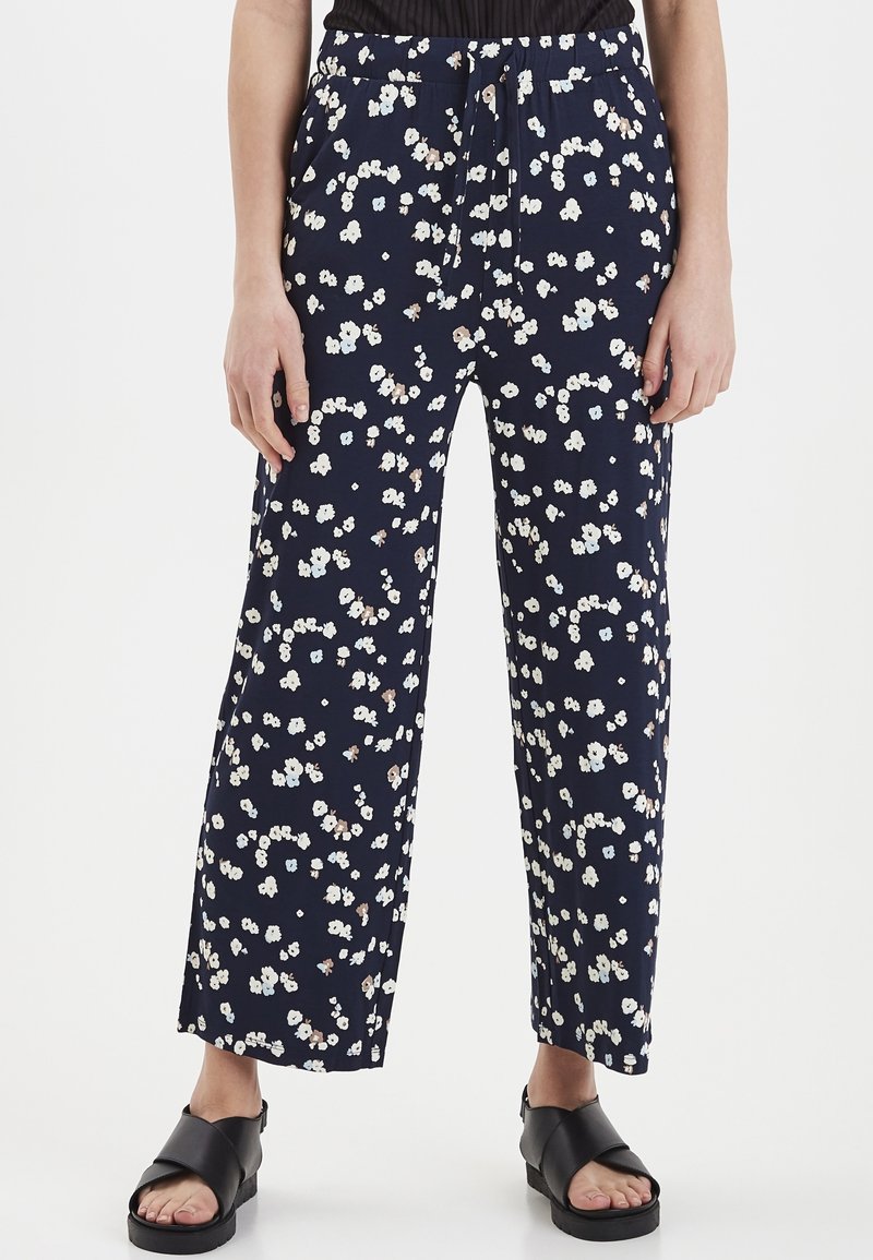 Marinblå vida byxor med liten blommönster i vitt och beige. Har ett elastiskt midjeband med dragsko. Lättviktsmaterial.