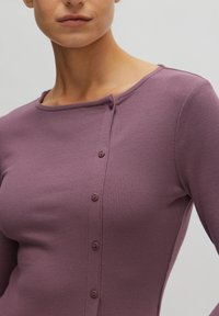 Gestreifter Langarm-Top in sanftem Mauve mit Bootsausschnitt, versehen mit einer Knopfleiste auf der linken Seite und einer figurbetonten Silhouette.