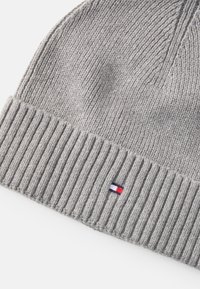 Hallgrey kootud beanie, millel on ribadega krae ja väike logo punaste, valgete ja siniste aktsentidega. Pehme tekstuur, ümar kuju.