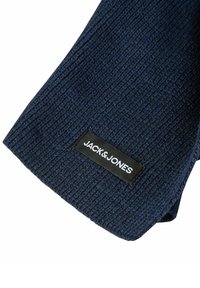 Donkerblauwe geribbelde sjaal met een rechthoekige vorm en een gestructureerde brei; bevat een zwart label met "JACK & JONES" in witte letters.
