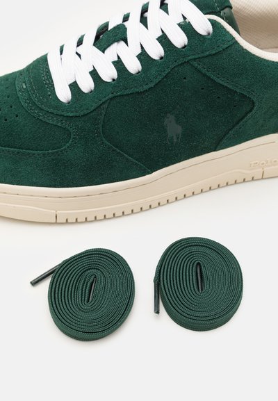 Πράσινα σουέτ αθλητικά παπούτσια με λευκές κορδόνες, διαθέτοντας διακριτικό λογότυπο και μπεζ σόλα. Περιλαμβάνονται δύο επιπλέον πράσινες κορδόνες.
