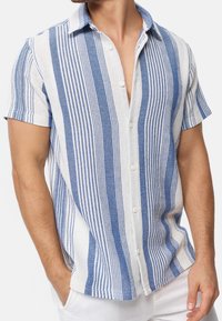 Camisa de manga corta con botones en tejido de sarga con rayas azules y blancas alternas, con cuello y un corte relajado.