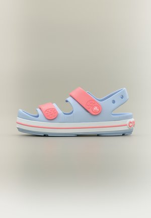 Jasnoniebieska sandał z różowymi regulowanymi paskami, białą podeszwą z różowym obszyciem i otworami wentylacyjnymi na neutralnym tle.