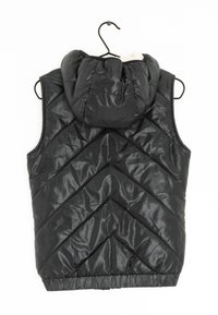 Schwarze, aufgeplusterte Weste mit Kapuze, die ein gestepptes Chevron-Muster, einen elastischen Bund und eine glatte, glänzende Textur aufweist. Hängt an einem Haken.