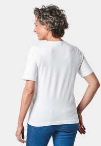 Witte T-shirt met korte mouwen van een zachte stof, met een ronde halslijn, een relaxte pasvorm en een glad oppervlak, gedragen met een blauwe spijkerbroek.