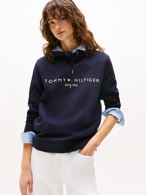 Navy cotton hoodie with a front logo, featuring a drawstring hood and blue cuff accents, paired with white pants.