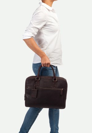 Dunkelbraune Leder-Laptoptasche mit zwei Griffen, Reißverschlussfächern und einem kleinen angebundenen Etikett. Sie hat eine strukturierten Oberfläche und rechteckige Form.