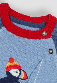 Blauer Strickpullover mit einem rot-blauen Rippkragen. Verfügt über eine detaillierte Puffin-Stickerei und einen Druckknopf an der Schulter.