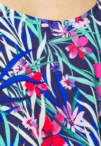 Top floral com fundo azul marinho e flores coloridas em rosa, vermelho e roxo, realçadas por folhas verdes, e um decote arredondado.