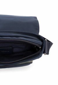 Granatowa materiałowa torba z zamkiem błyskawicznym, wewnętrzną kieszenią i regulowanym paskiem. Gładka tekstura z subtelnymi detalami szwów.