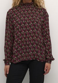 Schwarze Bluse mit floralen Mustern in Rosa und Creme, hoher Kragen mit Raffungsdetails, lange Ärmel mit Knopfmanschetten, leichtes Material.